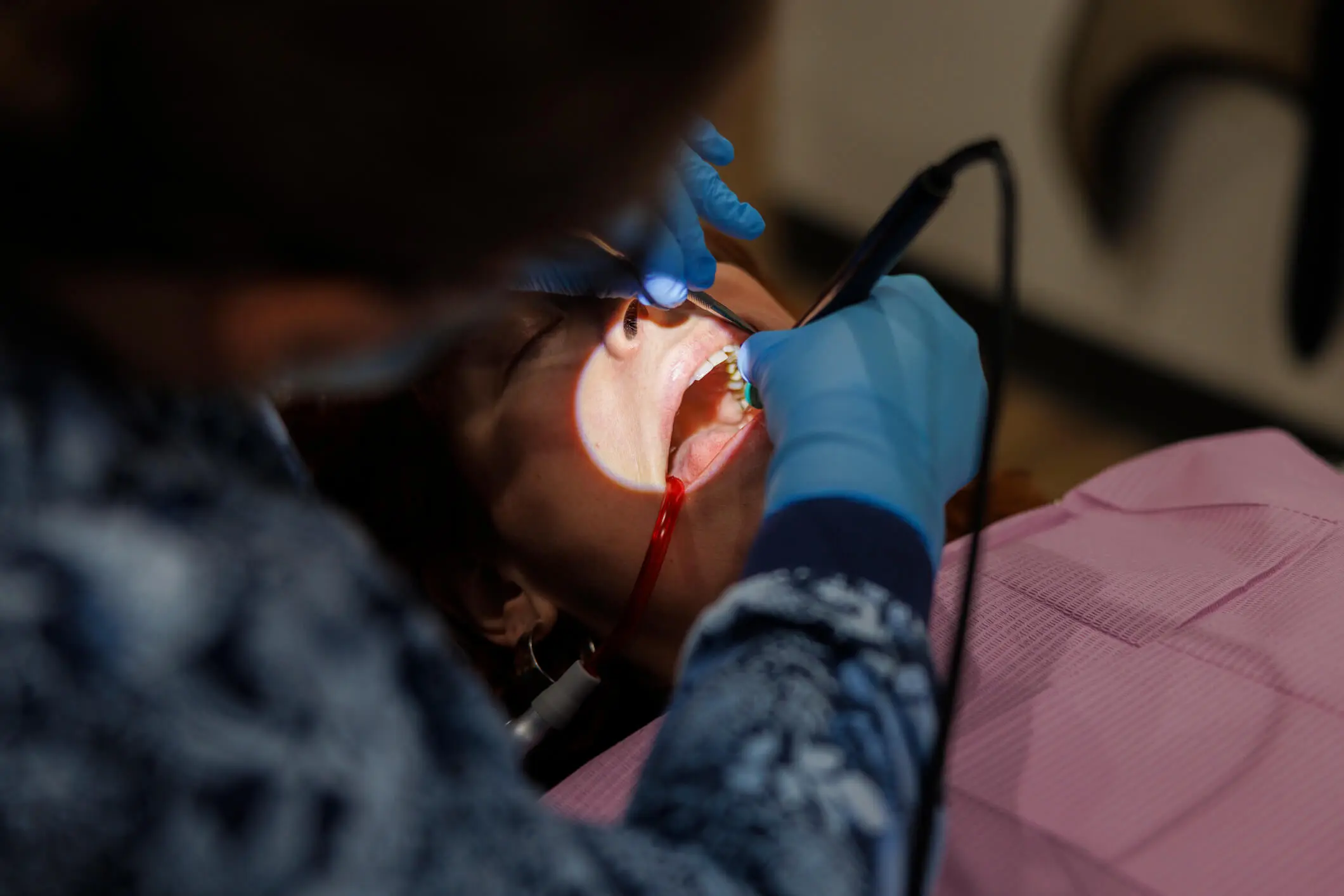 Dentist examining patient's teeth with tools.