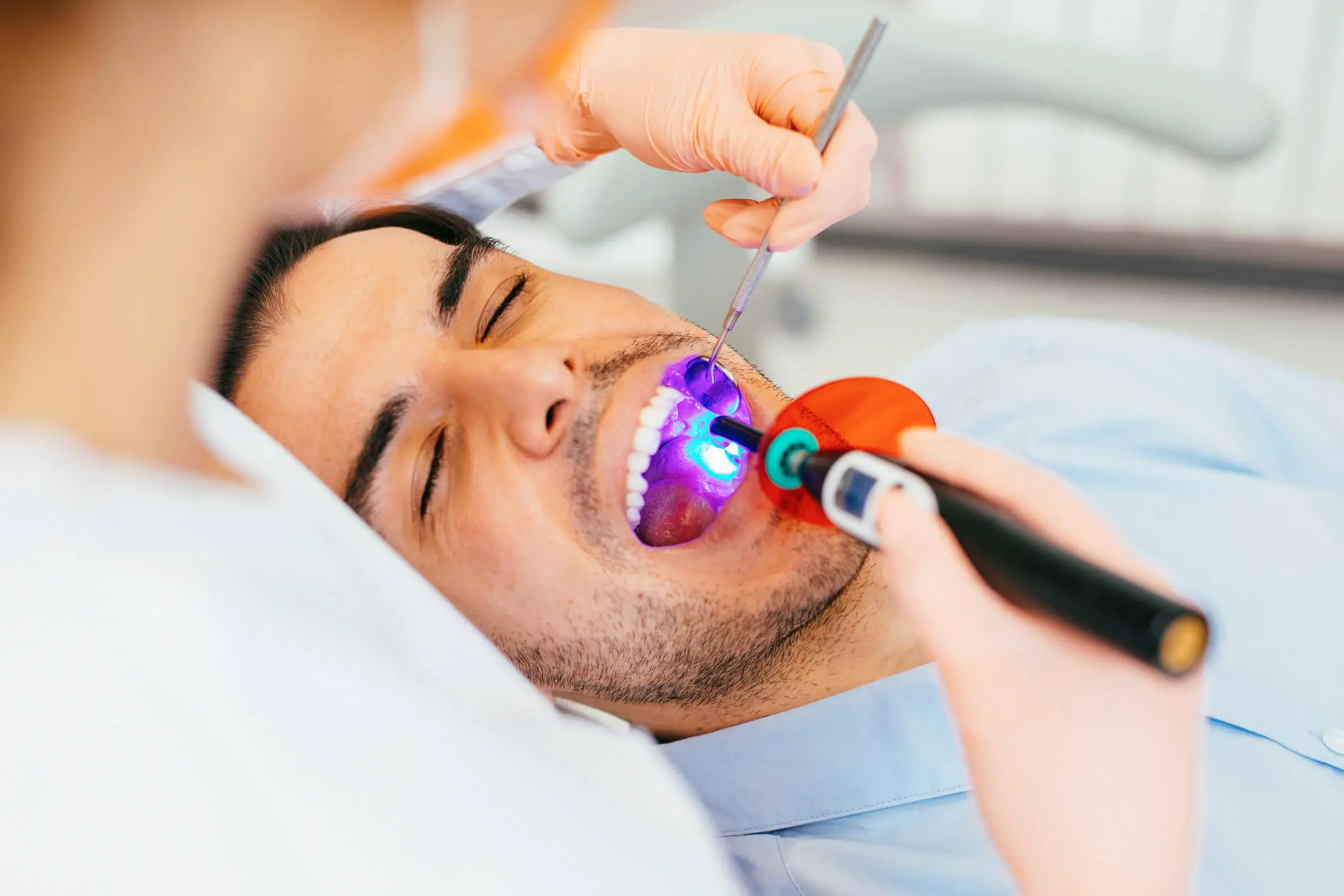 Patient receiving dental treatment with curing light.